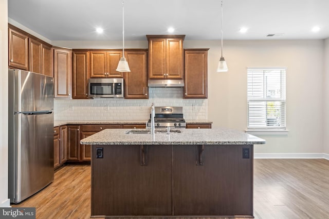 kitchen featuring light stone counters, sink, decorative light fixtures, and appliances with stainless steel finishes