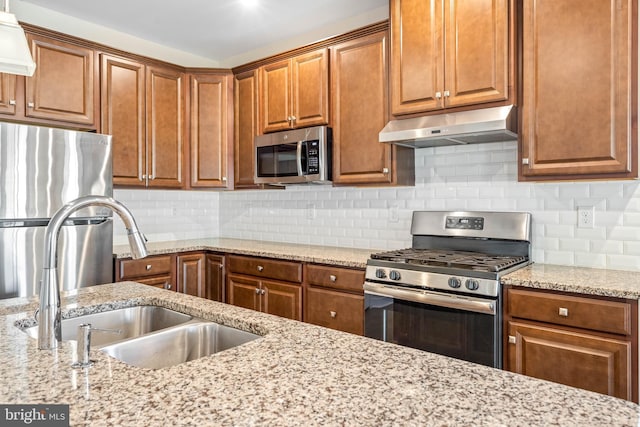 kitchen featuring sink, decorative backsplash, light stone countertops, and appliances with stainless steel finishes