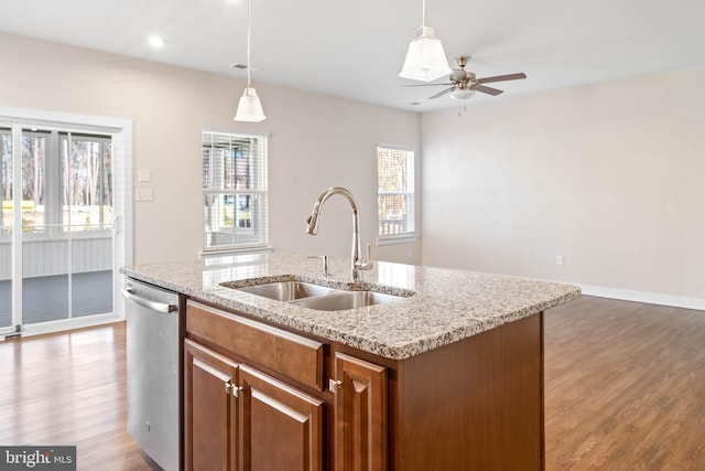 kitchen featuring pendant lighting, stainless steel dishwasher, sink, and a center island with sink