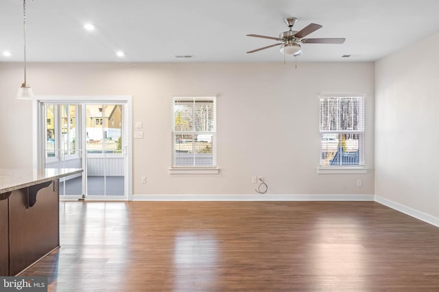 unfurnished living room featuring ceiling fan, dark hardwood / wood-style floors, and a healthy amount of sunlight