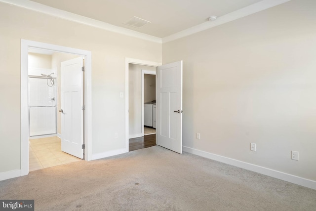 unfurnished bedroom with light carpet, ornamental molding, independent washer and dryer, and ensuite bathroom