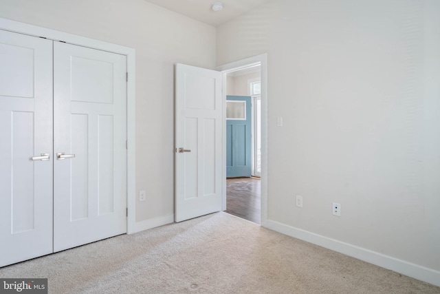 unfurnished bedroom featuring light colored carpet and a closet