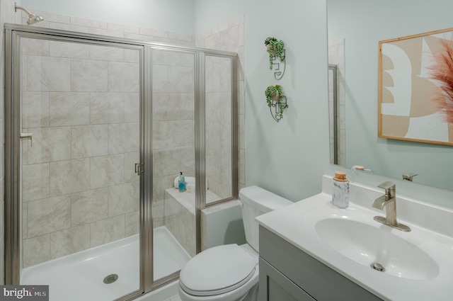 bathroom featuring a shower with door, vanity, and toilet