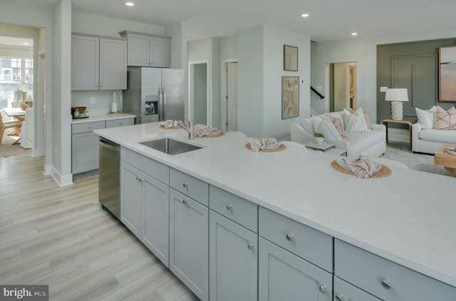 kitchen featuring light wood-type flooring, appliances with stainless steel finishes, sink, and gray cabinetry