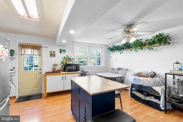 kitchen featuring blue cabinets, stainless steel fridge, white cabinets, a center island, and light hardwood / wood-style floors