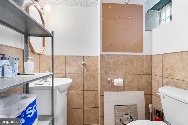 bathroom featuring vanity, tile walls, and toilet