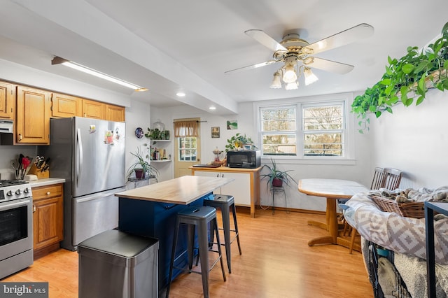 kitchen with ceiling fan, appliances with stainless steel finishes, light hardwood / wood-style floors, a kitchen bar, and breakfast area