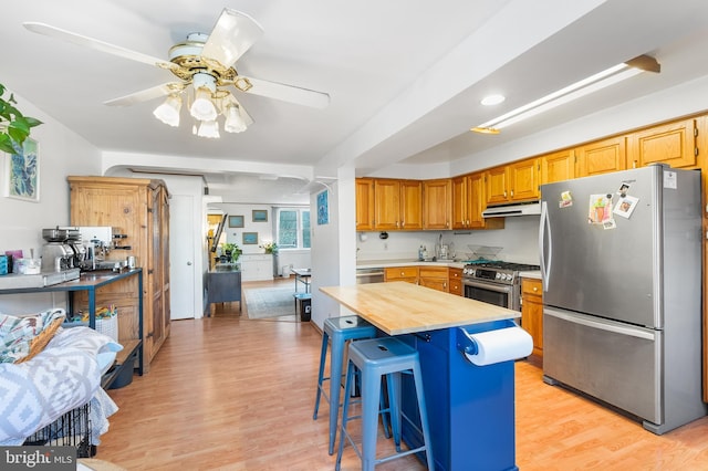 kitchen featuring stainless steel appliances, butcher block counters, a breakfast bar, and light wood-type flooring