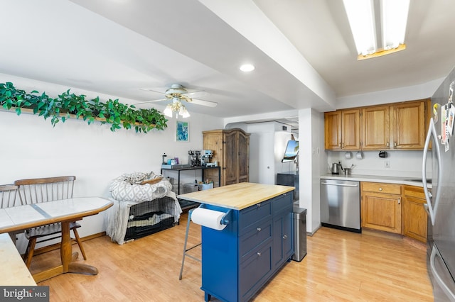 kitchen featuring a breakfast bar, wooden counters, a center island, stainless steel appliances, and light hardwood / wood-style flooring