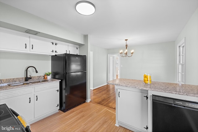 kitchen with white cabinetry, sink, decorative light fixtures, and black appliances