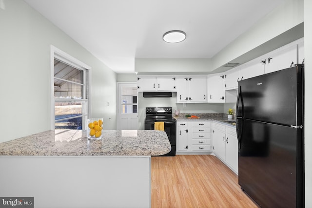 kitchen with black appliances, white cabinets, light stone counters, kitchen peninsula, and light hardwood / wood-style flooring