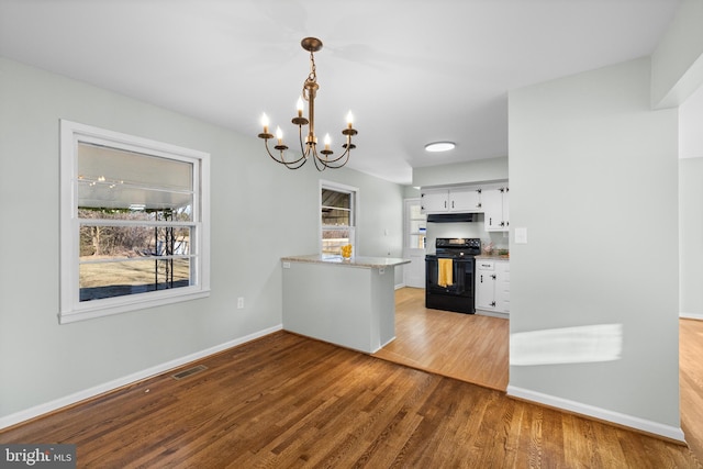 kitchen with hanging light fixtures, wood-type flooring, black electric range, white cabinets, and kitchen peninsula