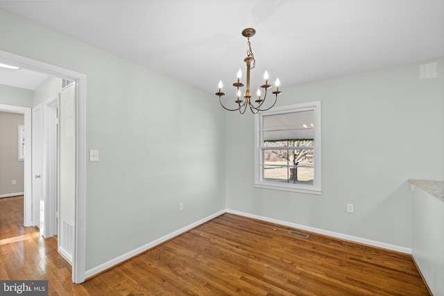 empty room with an inviting chandelier and wood-type flooring