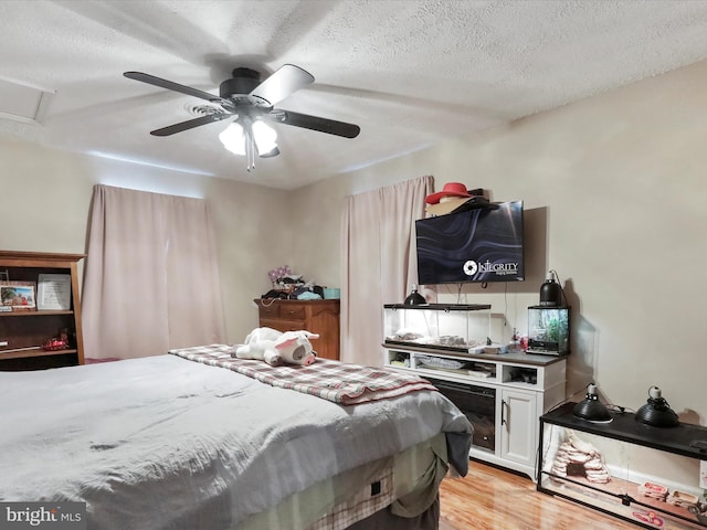 bedroom featuring ceiling fan, a textured ceiling, and light hardwood / wood-style flooring