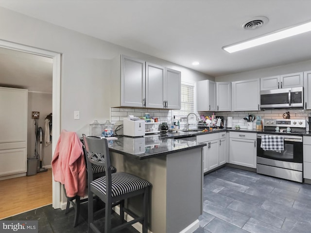 kitchen with stainless steel appliances, a breakfast bar, white cabinets, and backsplash