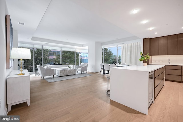 kitchen with sink, a breakfast bar area, tasteful backsplash, a center island, and light wood-type flooring