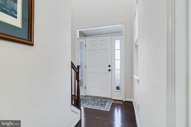 entrance foyer featuring dark wood-style floors, baseboards, stairway, and visible vents