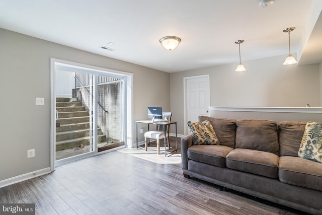 living room with stairs, visible vents, baseboards, and wood finished floors