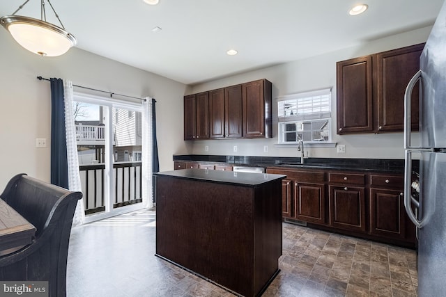 kitchen featuring a sink, appliances with stainless steel finishes, dark countertops, and a kitchen island