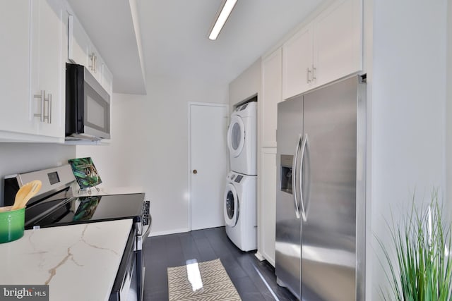 laundry area featuring stacked washer and dryer and dark hardwood / wood-style flooring