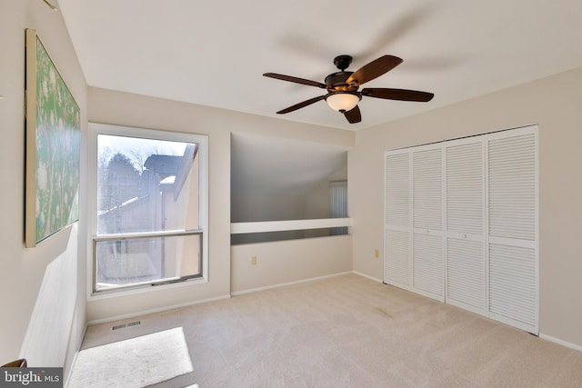 unfurnished bedroom with multiple windows, light colored carpet, ceiling fan, and a closet