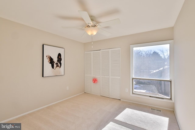 unfurnished bedroom with light carpet, a closet, and ceiling fan