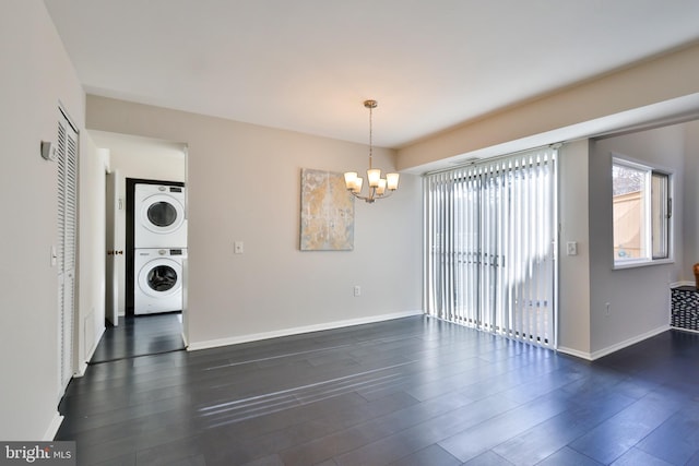 unfurnished dining area featuring dark hardwood / wood-style flooring, stacked washer / drying machine, and a notable chandelier