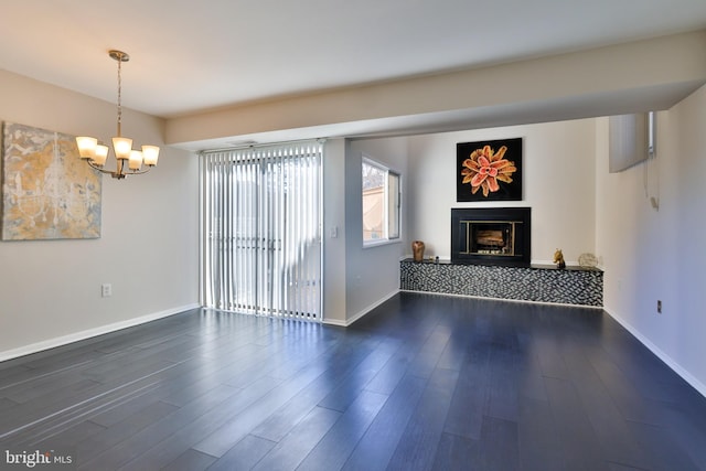 unfurnished living room with a notable chandelier and dark hardwood / wood-style flooring