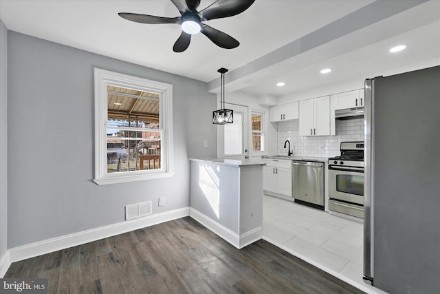 kitchen with white cabinetry, a wealth of natural light, pendant lighting, stainless steel appliances, and decorative backsplash