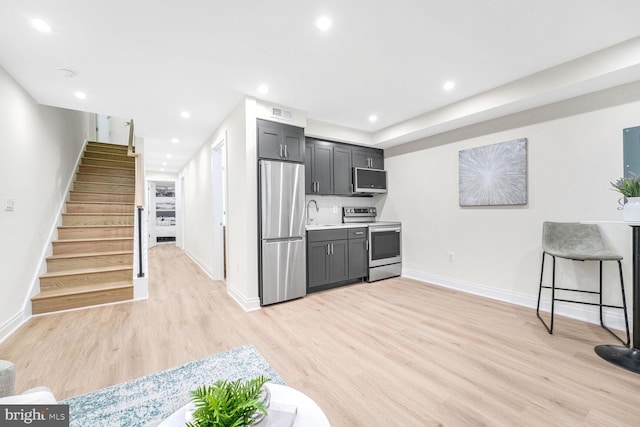 kitchen with tasteful backsplash, appliances with stainless steel finishes, a kitchen breakfast bar, and light hardwood / wood-style flooring