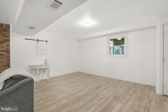 basement featuring a barn door and light hardwood / wood-style flooring