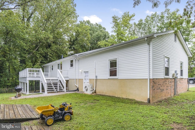 rear view of house featuring a wooden deck, a lawn, and ac unit