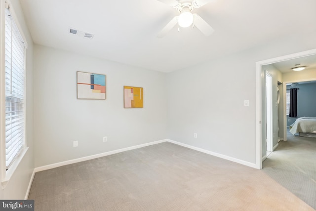 spare room with ceiling fan, light colored carpet, and a healthy amount of sunlight