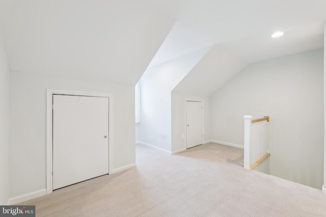 bonus room with lofted ceiling and light carpet