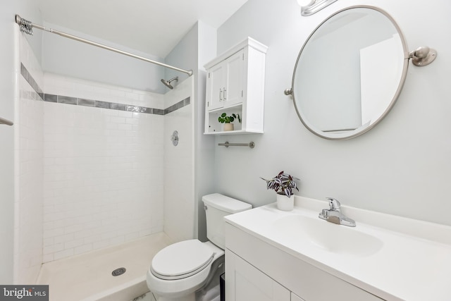 bathroom featuring vanity, toilet, and a tile shower