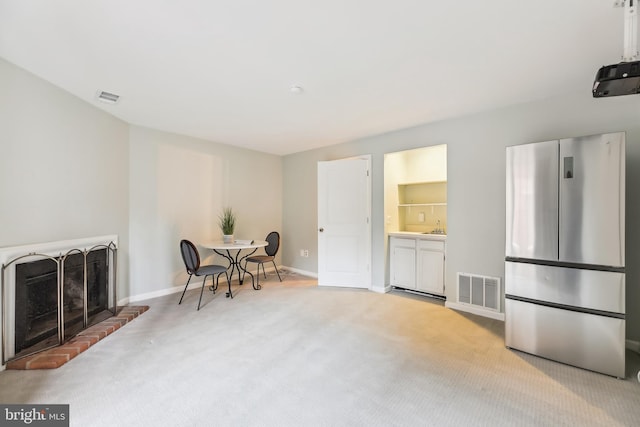 sitting room with light colored carpet, a fireplace, and sink