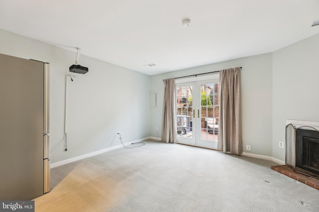 unfurnished living room featuring a fireplace, french doors, and carpet