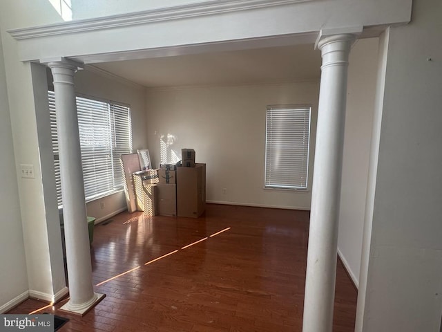 corridor featuring decorative columns, ornamental molding, and dark wood-type flooring