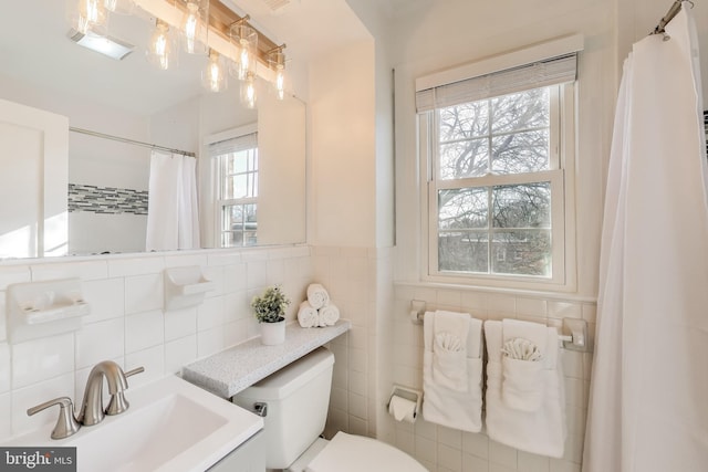 bathroom featuring vanity, tile walls, and toilet