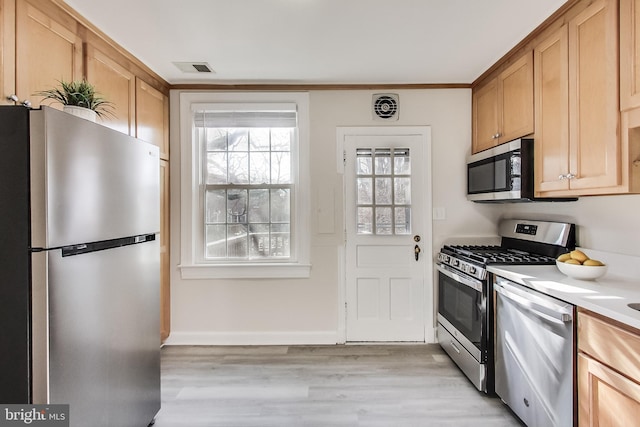 kitchen with appliances with stainless steel finishes, light brown cabinetry, and light hardwood / wood-style flooring