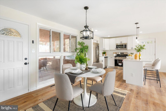 dining area with a healthy amount of sunlight, a chandelier, and light hardwood / wood-style flooring