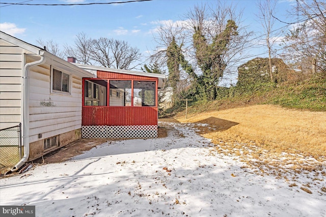 yard covered in snow featuring a sunroom