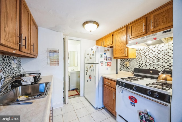 kitchen with light tile patterned flooring, white appliances, sink, and backsplash