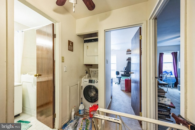 clothes washing area with stacked washer / dryer, light carpet, and ceiling fan