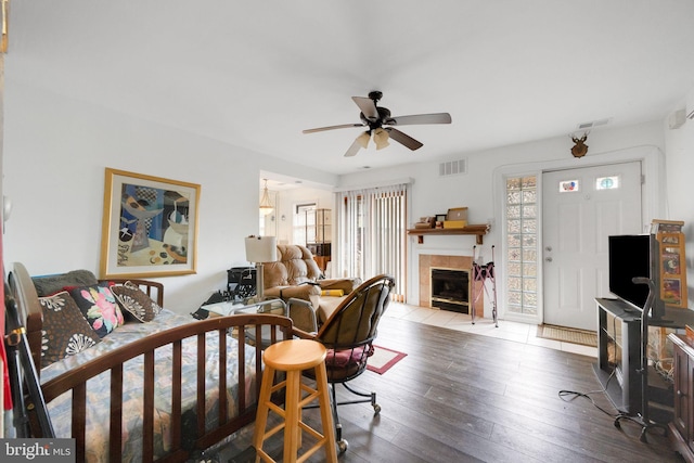 living room featuring a tile fireplace, ceiling fan, and light wood-type flooring