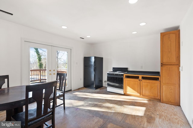 kitchen with french doors, black fridge, hardwood / wood-style floors, and white gas range oven