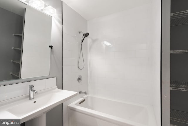 bathroom featuring tiled shower / bath combo, sink, and backsplash