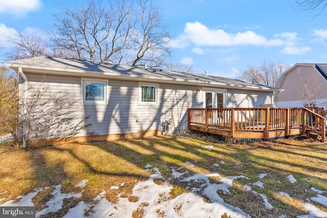 snow covered rear of property featuring a wooden deck and a yard