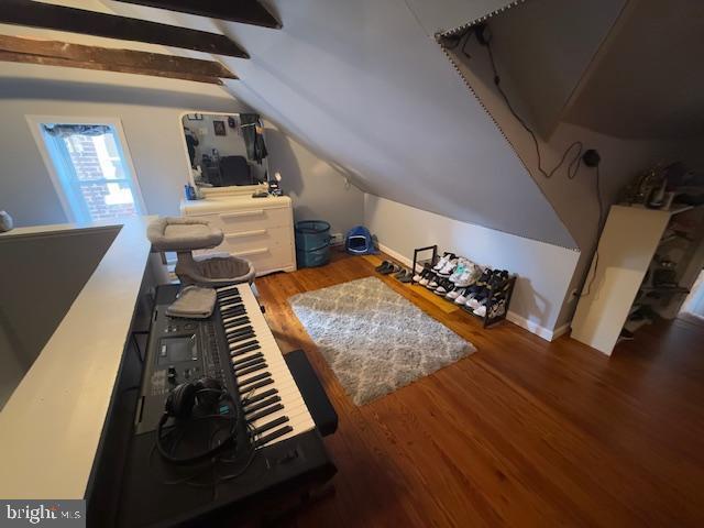 bonus room with dark wood-type flooring and vaulted ceiling with beams