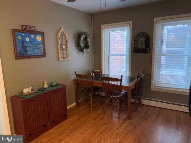 dining area with hardwood / wood-style flooring, ceiling fan, and baseboard heating